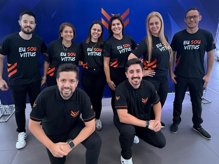 Equipe Vittus reunida em frente ao painel da marca com camisetas Eu sou Vittus